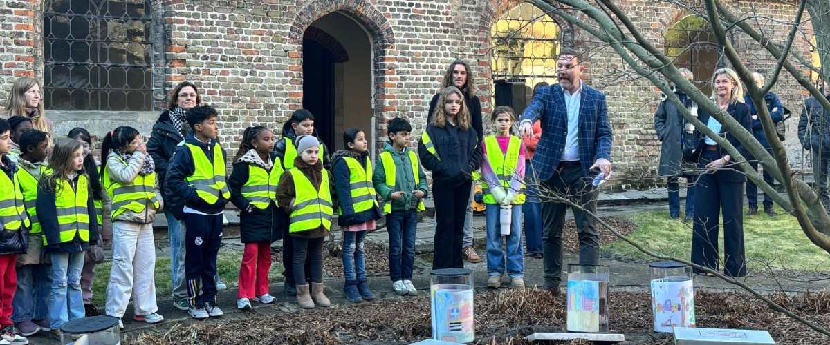 Enkele leerlingen laten hun tekeningen begraven in een tijdcapsule in de tuin van de Sint-Godelieveabdij.